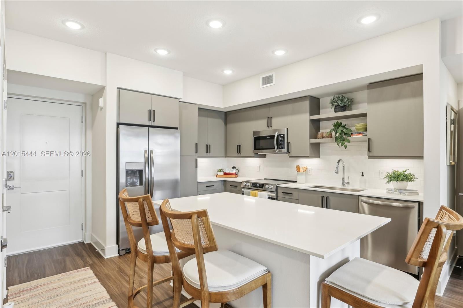 A modern kitchen features gray cabinets, stainless steel appliances, and a white quartz island — 9030 SW 158th Ave # 211, Miami FL 33196, MIAMI, FL