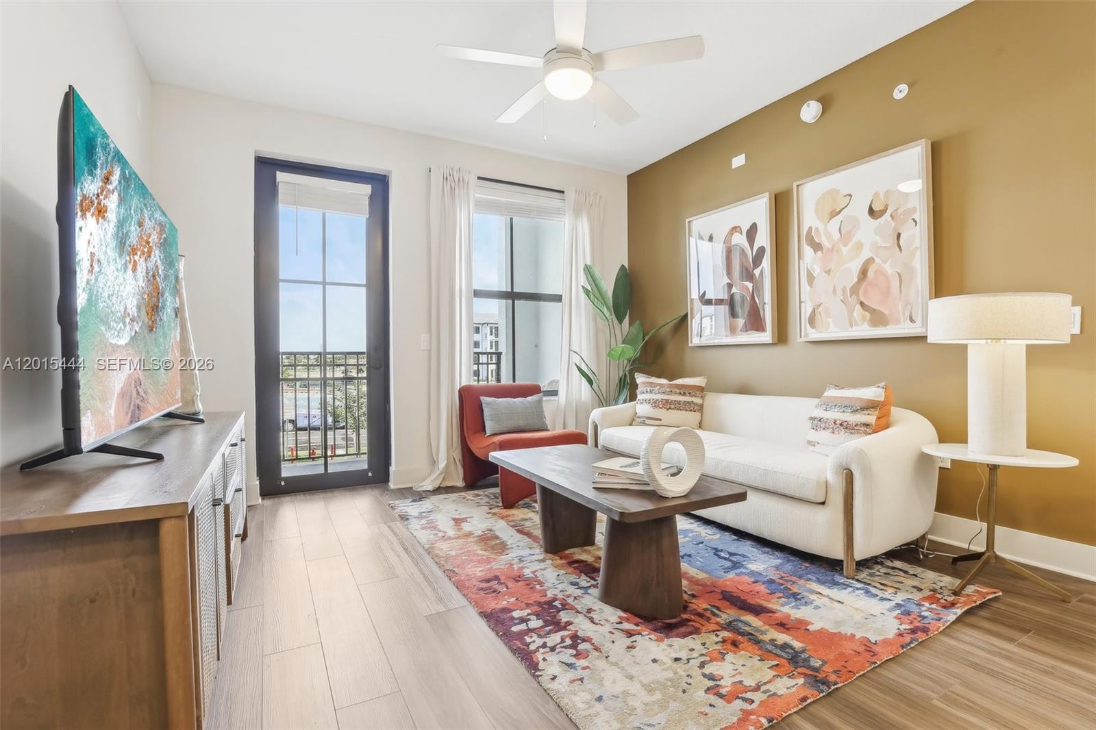 A living room features a white sofa, a colorful area rug, and a balcony door — 9030 SW 158th Ave # 211, Miami FL 33196, MIAMI, FL