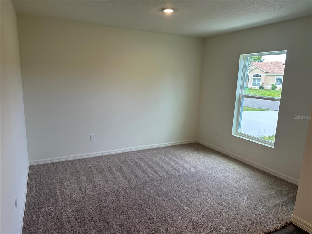 An empty bedroom features beige walls, gray carpeting, and a single window — 18 PICKWOOD PLACE, PALM COAST, FL