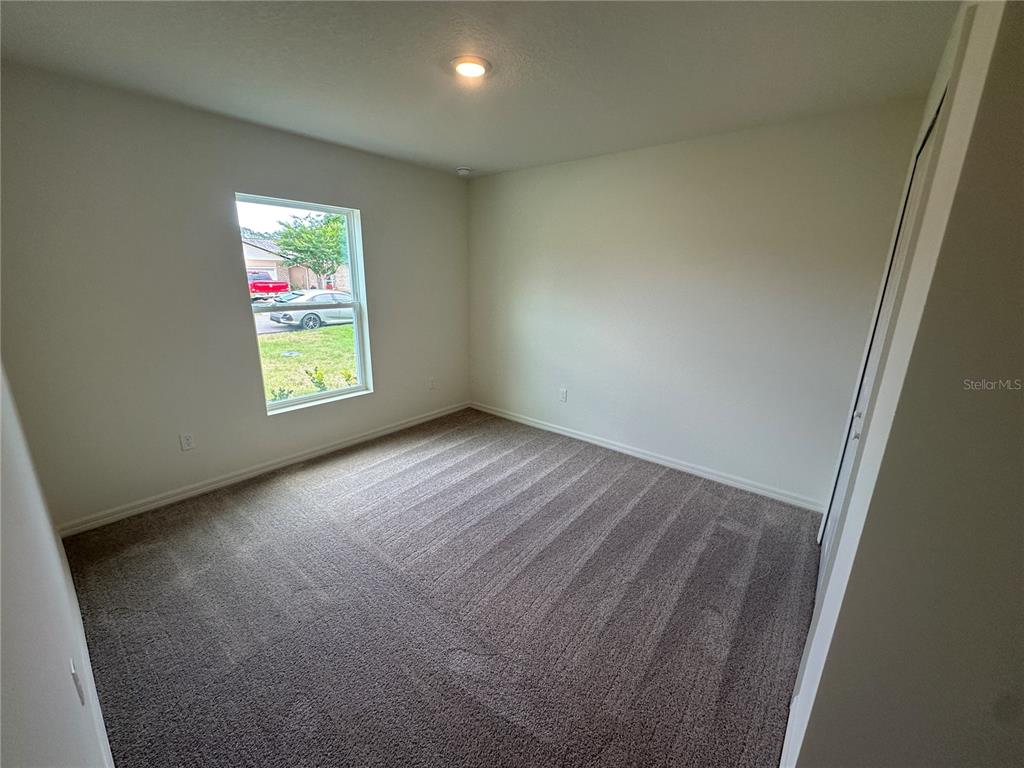 An empty bedroom features neutral walls, gray carpeting, a single window, and a closet — 18 PICKWOOD PLACE, PALM COAST, FL