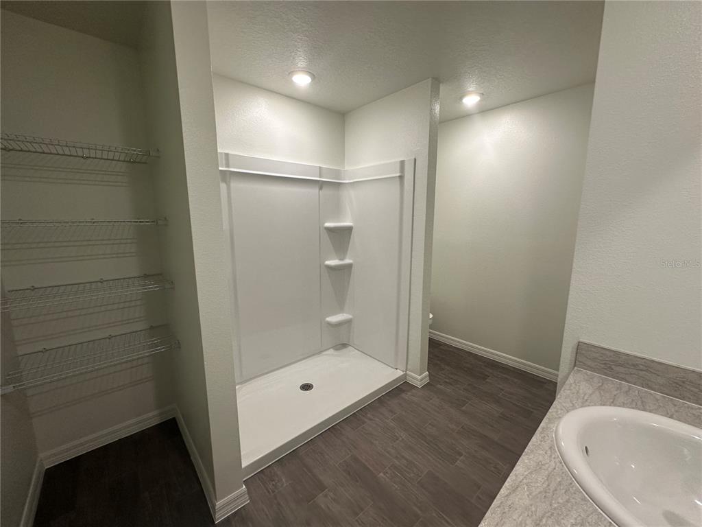 A bathroom features a walk-in shower, wire shelving, and a vanity with a sink — 18 PICKWOOD PLACE, PALM COAST, FL