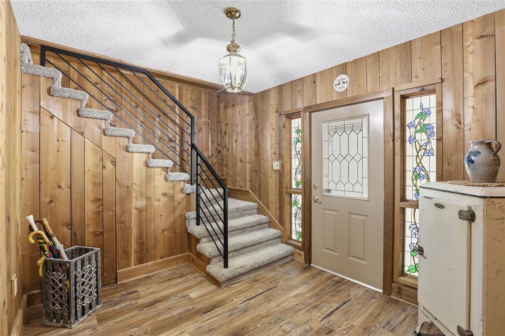 An entryway features wood-paneled walls, a carpeted staircase with a black railing, and a front door — 818 NE 783 STREET, OLD TOWN, FL