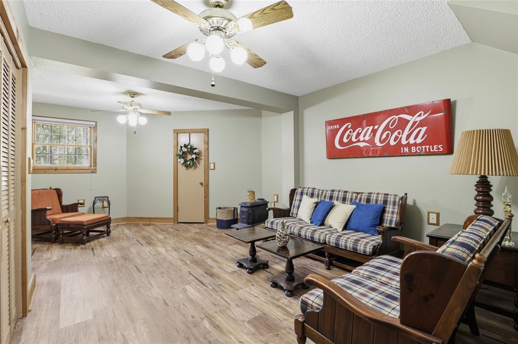 A living room features wood-look flooring, a plaid sofa, and a large Coca-Cola wall sign — 818 NE 783 STREET, OLD TOWN, FL