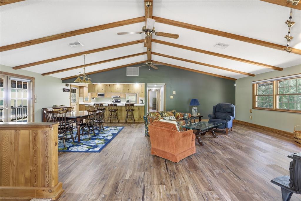 An open-concept living and dining area features vaulted ceilings with exposed wood beams — 818 NE 783 STREET, OLD TOWN, FL