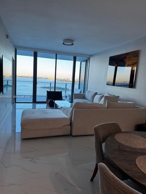 A modern living room features a large sectional sofa, tile flooring, and floor-to-ceiling windows — 700 NE 24 # 2206, Miami FL 33137, MIAMI, FL