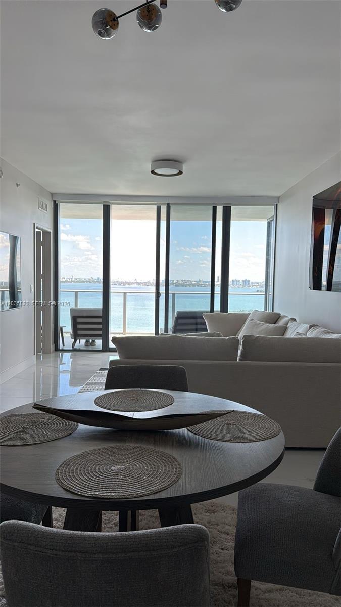 A dining area with a round table overlooks a living room and a waterfront balcony — 700 NE 24 # 2206, Miami FL 33137, MIAMI, FL