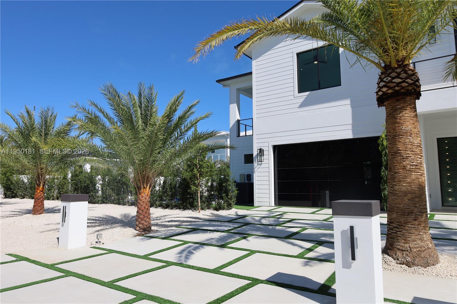 A modern house features a white exterior, a glass garage door, and a paved driveway — 258 Caribbean Dr, Key Largo FL 33037, KEY LARGO, FL