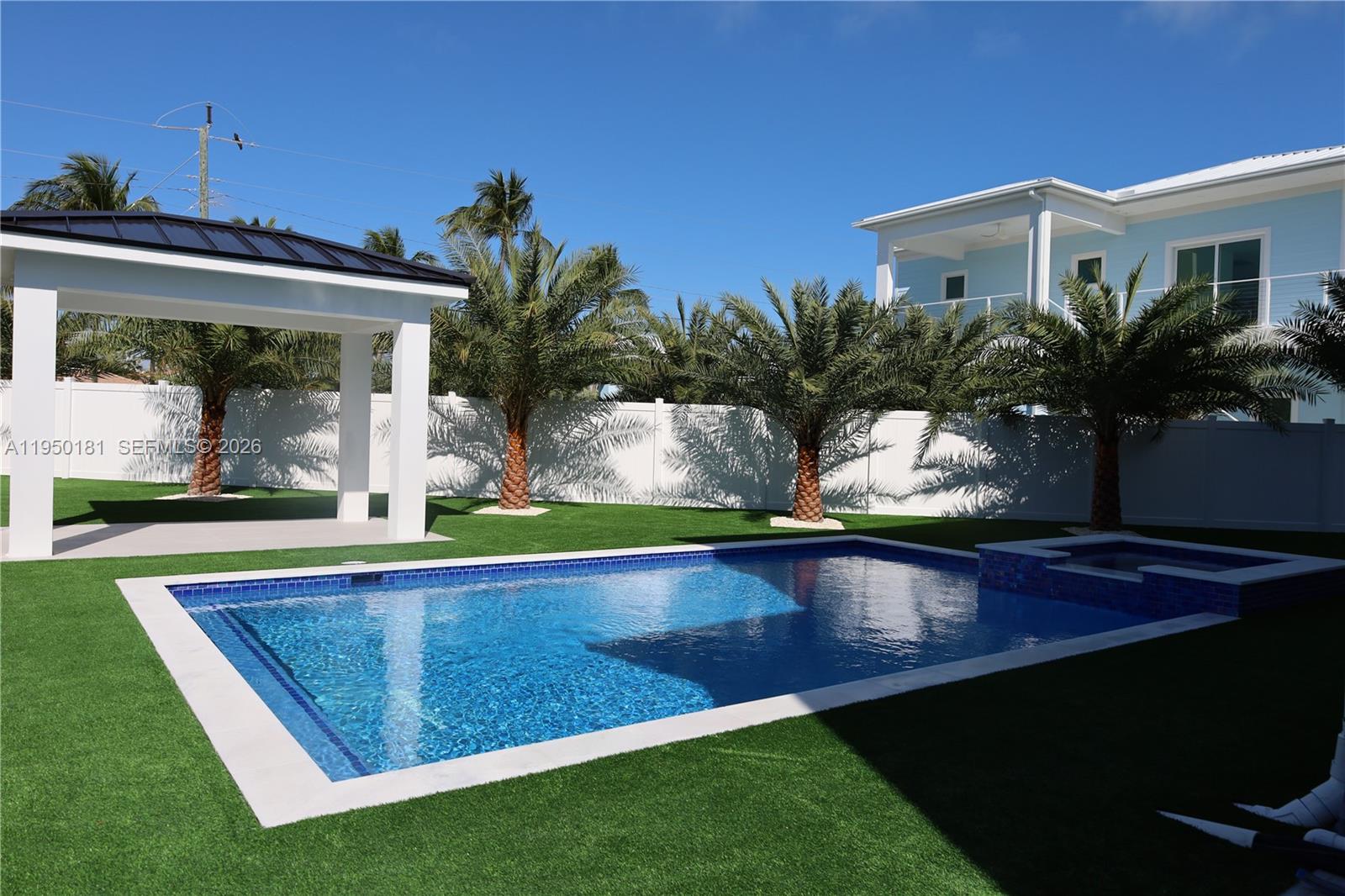 A backyard features a swimming pool, a covered patio, and palm trees on artificial turf — 258 Caribbean Dr, Key Largo FL 33037, KEY LARGO, FL