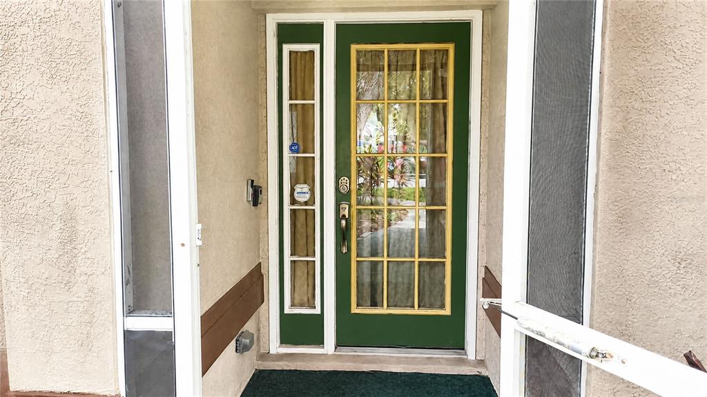 A green front door with a glass pane and a matching side light — 12021 68TH STREET, LARGO, FL