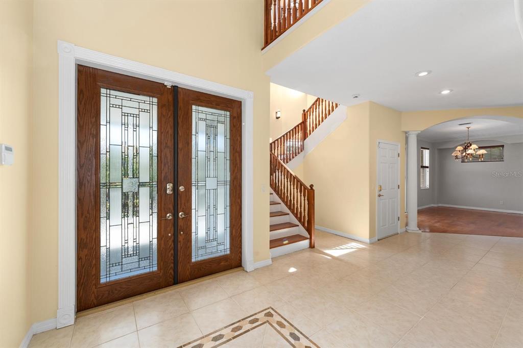 A foyer with tile flooring, a double front door, and a wooden staircase — 921 POINT SEASIDE DRIVE, CRYSTAL BEACH, FL