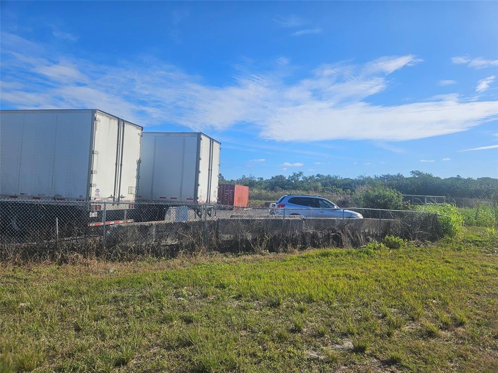 Two semi-trailers and a parked car sit behind a chain-link fence in a grassy lot — 12355 US HWY 19 N, CLEARWATER, FL
