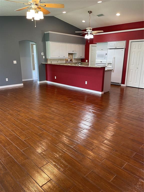 A kitchen with white cabinets and a red breakfast bar overlooks a large living area — 9461 MIAMI CIRCLE, PORT CHARLOTTE, FL