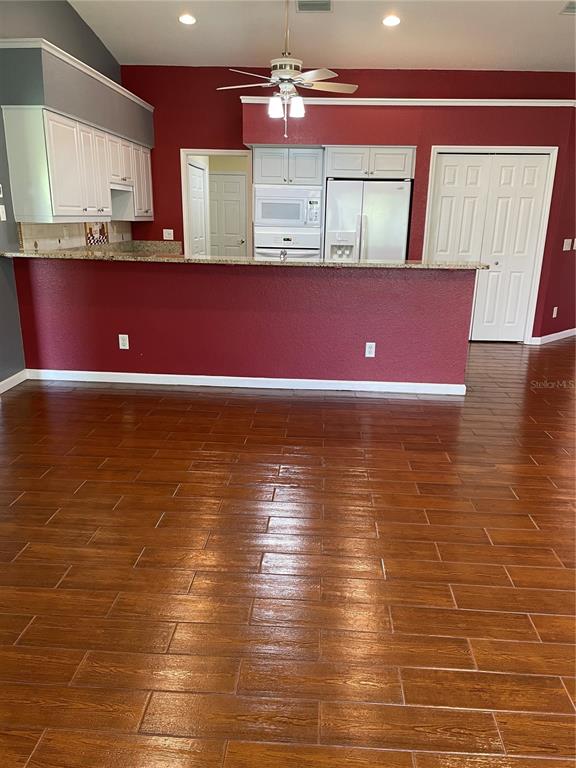 A kitchen with white cabinets, a red wall, and wood-look tile flooring — 9461 MIAMI CIRCLE, PORT CHARLOTTE, FL