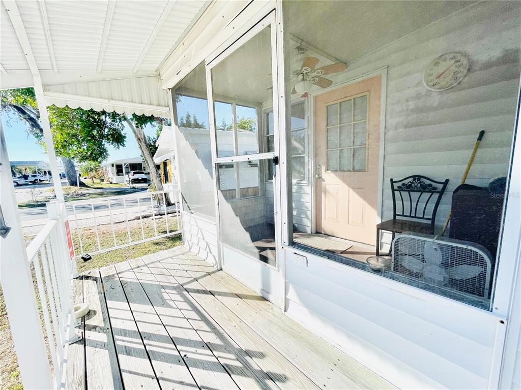 A wooden porch with a screened-in section, a light-colored door, and a ceiling fan — 3275 26TH AVENUE E UNIT 107, BRADENTON, FL