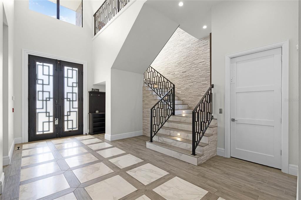 A bright foyer features a double front door, a marble-tiled floor, and a staircase — 1148 GRAND TRAVERSE PARKWAY, REUNION, FL