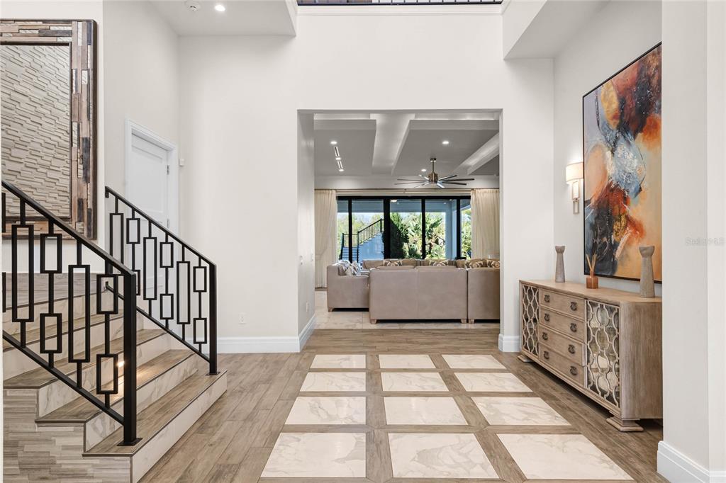 A bright entryway features a staircase with a geometric railing, tiled flooring, and a console table — 1148 GRAND TRAVERSE PARKWAY, REUNION, FL