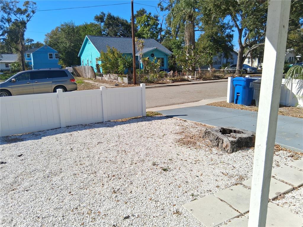 A gravel yard with a white vinyl fence, a tree stump, and a blue house — 2020 13TH STREET S, ST PETERSBURG, FL