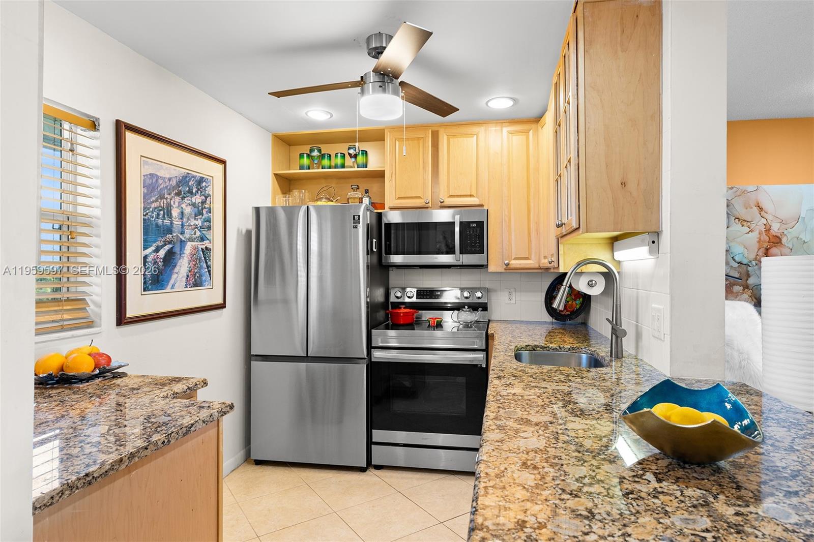 A kitchen features stainless steel appliances, light wood cabinets, and speckled granite countertops — 130 NE 26th Ave # 4040, Boynton Beach FL 33435, BOYNTON BEACH, FL