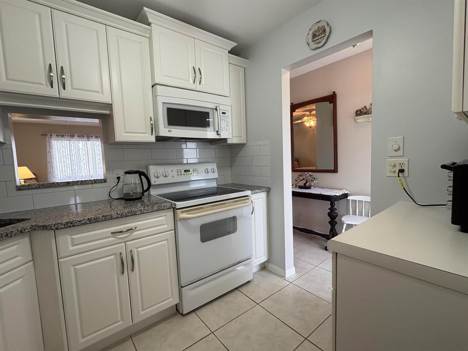 A kitchen with white cabinets, granite countertops, a white stove, and a tile floor — 108 NE 20th Avenue NE # 206, Boynton Beach FL 33435, BOYNTON BEACH, FL