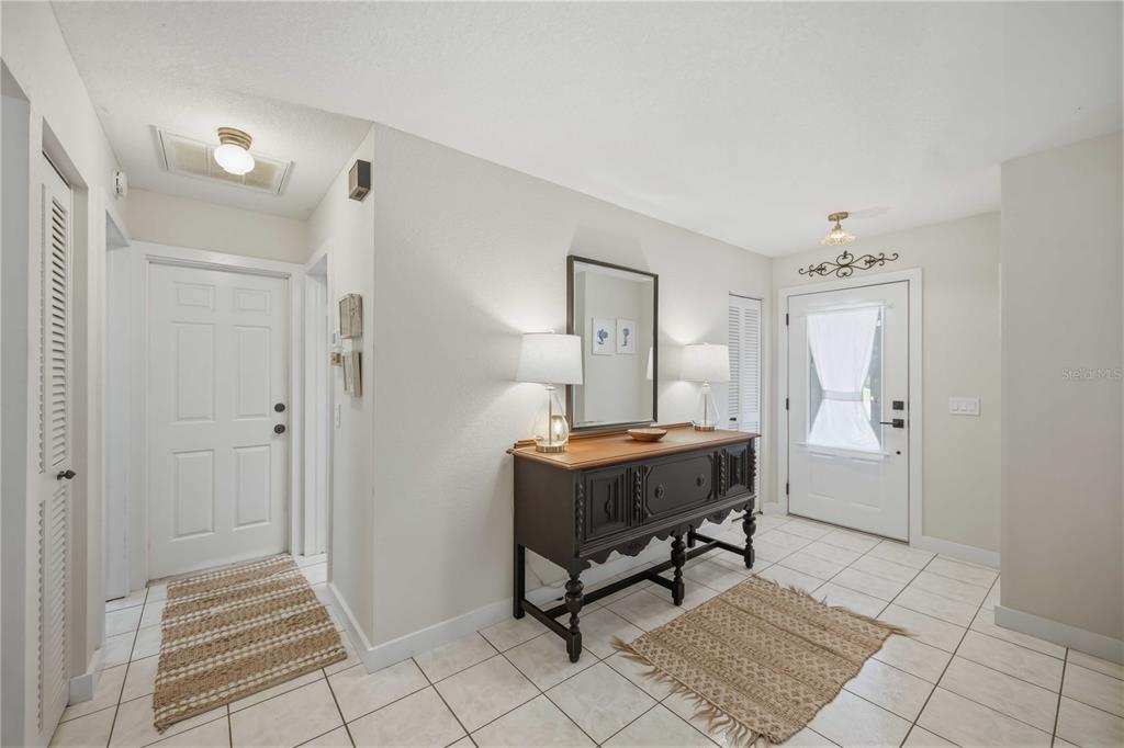 An entryway features tiled floors, a dark wood console table with lamps, and two doors — 23420 STEEPLE AVENUE, PORT CHARLOTTE, FL