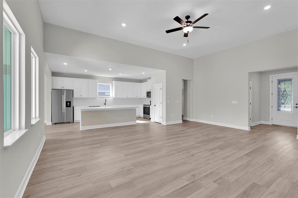An open-concept living area with light wood-look flooring, a kitchen, and a front entryway — 3 FIELDING LANE, PALM COAST, FL