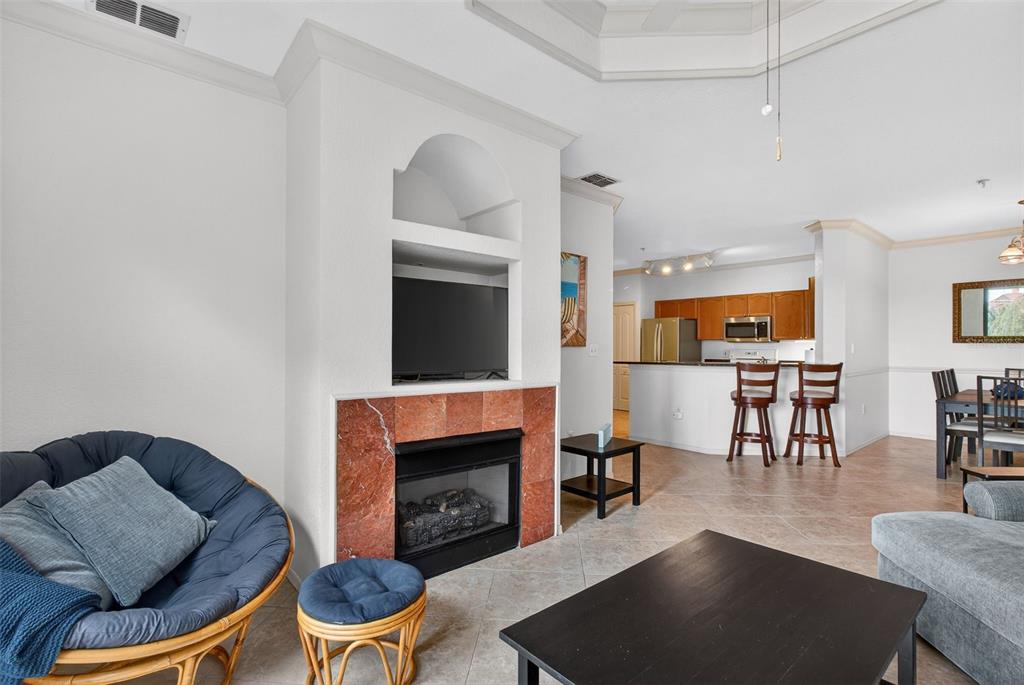 A living room features a red marble fireplace, a television niche, and an open kitchen — 2730 VIA TIVOLI UNIT 335A, CLEARWATER, FL