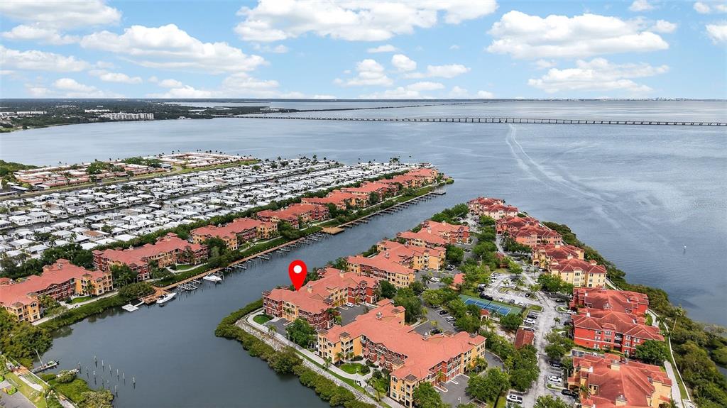 An aerial view shows a waterfront residential complex with red-roofed buildings and a boat dock — 2730 VIA TIVOLI UNIT 335A, CLEARWATER, FL