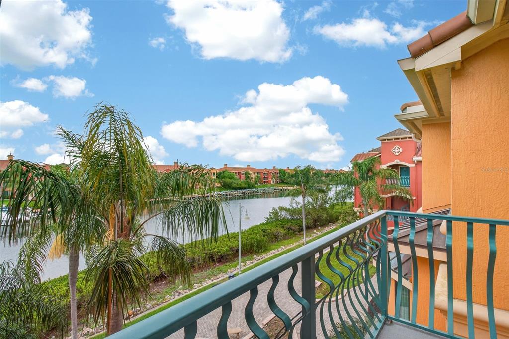 A view from a balcony overlooking a canal, palm trees, and Mediterranean-style apartment buildings — 2730 VIA TIVOLI UNIT 335A, CLEARWATER, FL