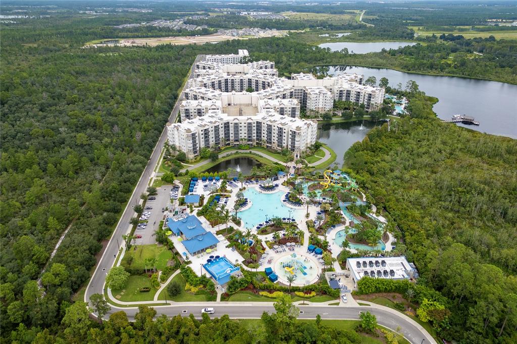 Aerial view of a large resort complex featuring a multi-story building, swimming pools, and waterslides — 14501 GROVE RESORT AVENUE UNIT 3642, WINTER GARDEN, FL