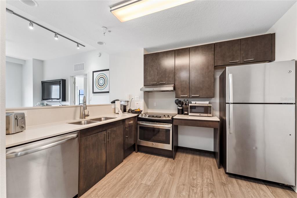 A modern kitchen features dark wood cabinets, stainless steel appliances, and light-colored countertops — 14501 GROVE RESORT AVENUE UNIT 3642, WINTER GARDEN, FL