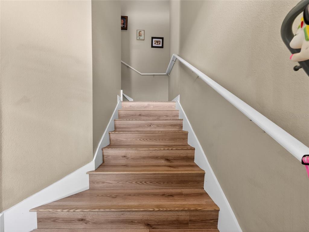 A wooden staircase with white handrails leads to a landing with framed wall art — 2811 SAN JACINTO CIRCLE, SANFORD, FL
