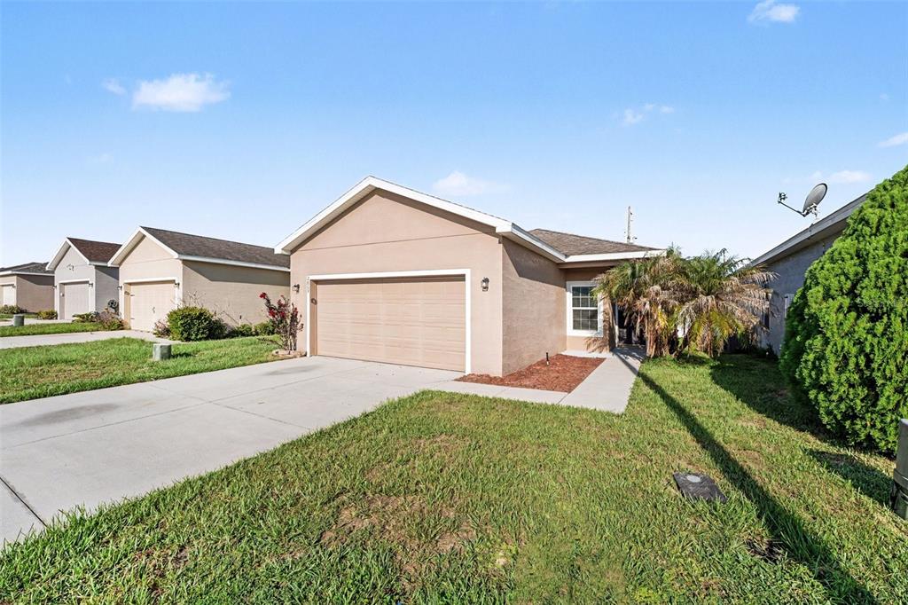 A tan single-story house with a two-car garage and a concrete driveway — 2865 WHISPERING TRAILS DRIVE, WINTER HAVEN, FL