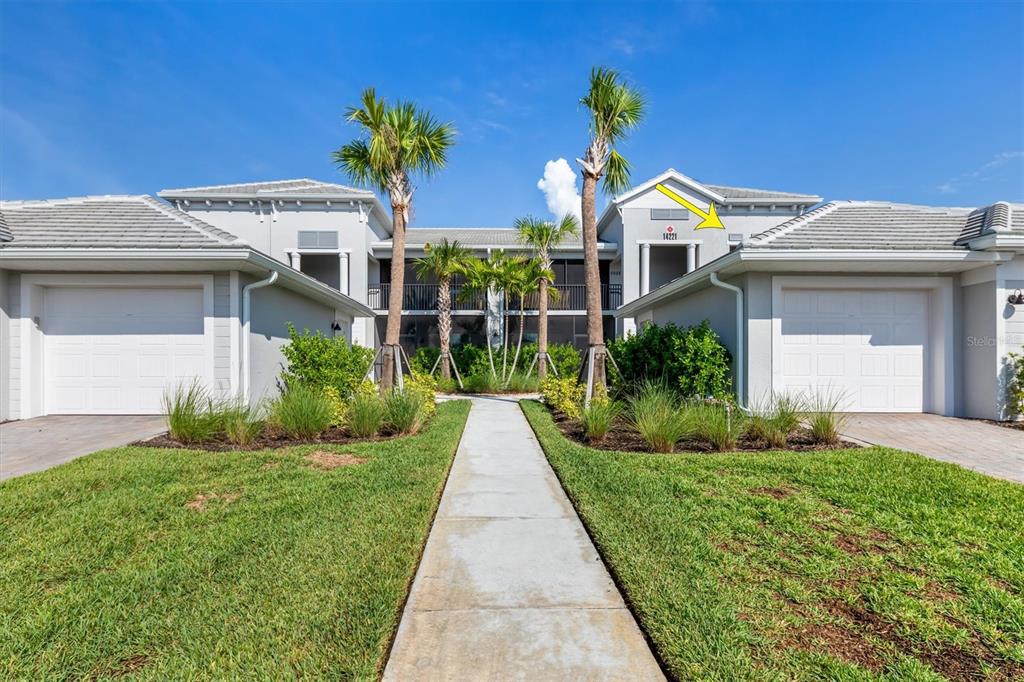 A view of a two-story residential building exterior with two garages and a central walkway — 14221 HERITAGE LANDING BOULEVARD UNIT 2026, PUNTA GORDA, FL