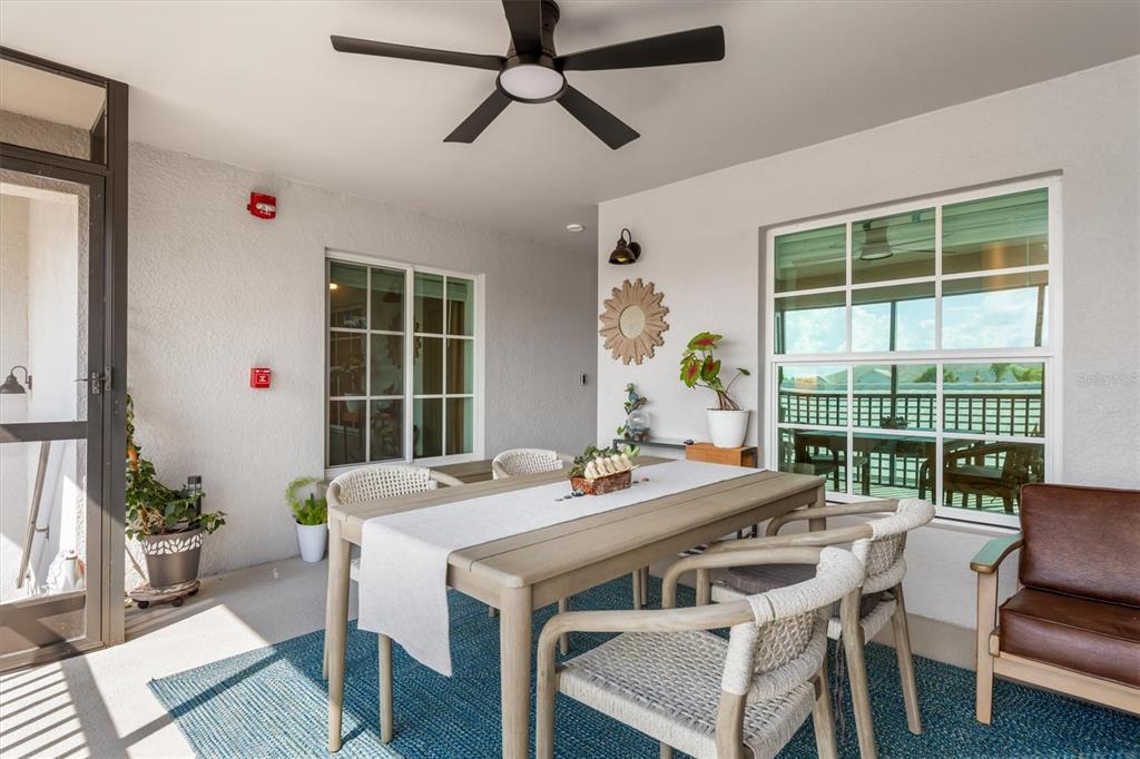 A covered patio features a dining table, woven chairs, a ceiling fan, and large windows — 14221 HERITAGE LANDING BOULEVARD UNIT 2026, PUNTA GORDA, FL