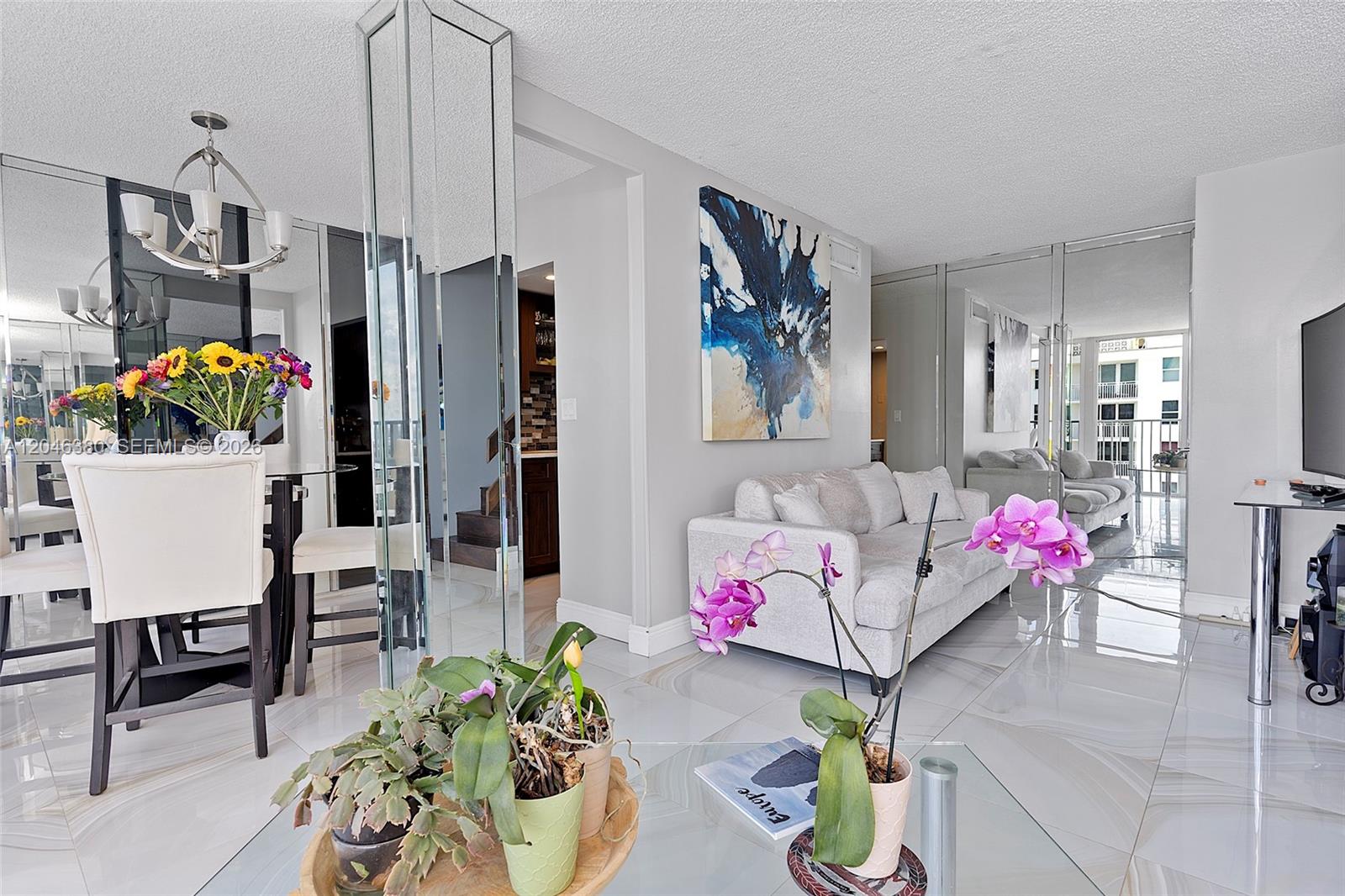 A living and dining area features white tile floors, mirrored walls, and contemporary furniture — 111 N BRINY AVE, Pompano Beach FL 33062, POMPANO BEACH, FL