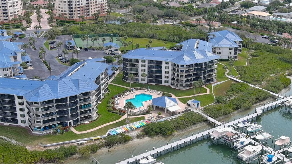 An aerial view shows multi-story apartment buildings with blue roofs, a swimming pool, and docks — 2700 N PENINSULA AVENUE UNIT 511, NEW SMYRNA BEACH, FL