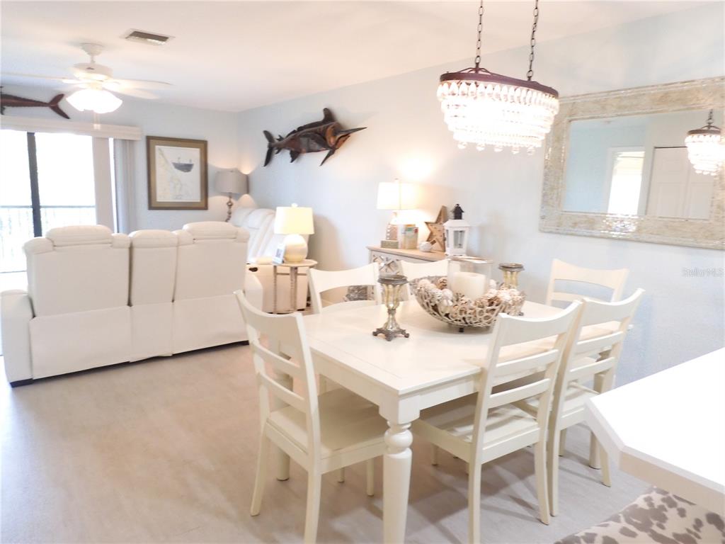 A dining area with a white table and chairs sits adjacent to a living room — 2700 N PENINSULA AVENUE UNIT 511, NEW SMYRNA BEACH, FL