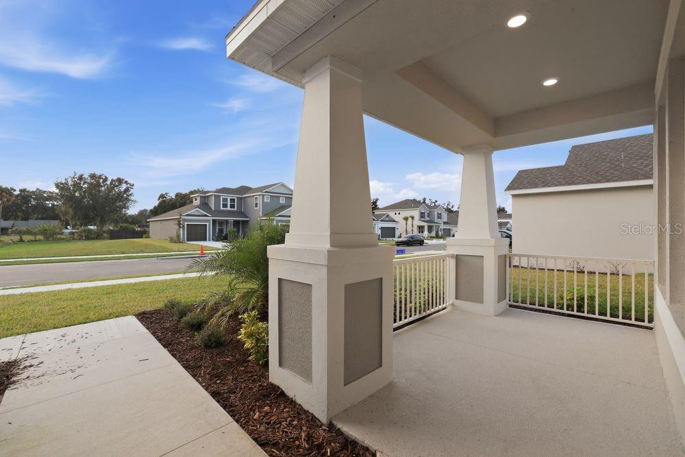 A covered front porch with white columns and railings overlooks a suburban street — 3328 LUMBER FALLS DRIVE, PLANT CITY, FL