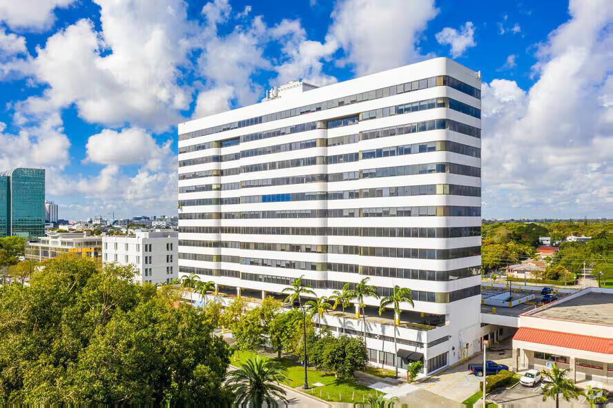 An aerial view of a tall, white office building surrounded by trees and parking lots — 4770 Biscayne Boulevard # 620, Miami FL 33137, MIAMI, FL