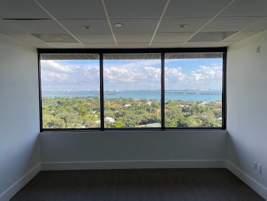 An empty office room features a large three-pane window overlooking a bay and city skyline — 4770 Biscayne Boulevard # 620, Miami FL 33137, MIAMI, FL