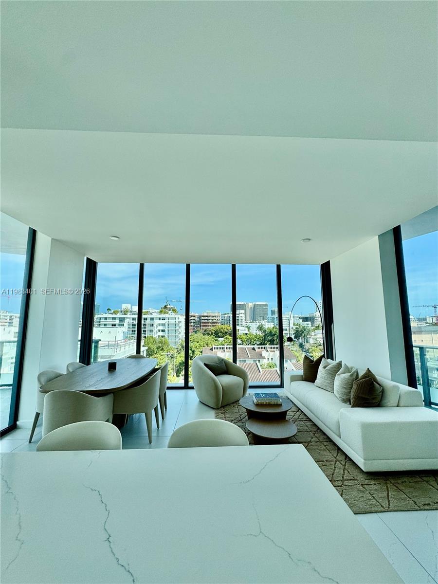 A modern living and dining area features floor-to-ceiling windows overlooking a city skyline — 9901 W Bay Harbor Drive # 506, Miami FL 33154, MIAMI, FL