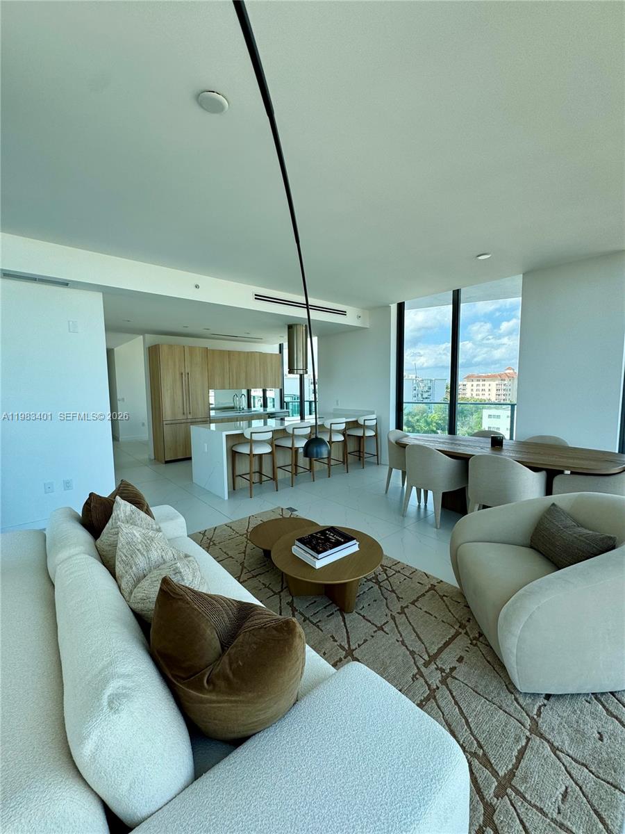 This open-concept living and dining area features modern furniture, light tile floors, and kitchen cabinetry — 9901 W Bay Harbor Drive # 506, Miami FL 33154, MIAMI, FL
