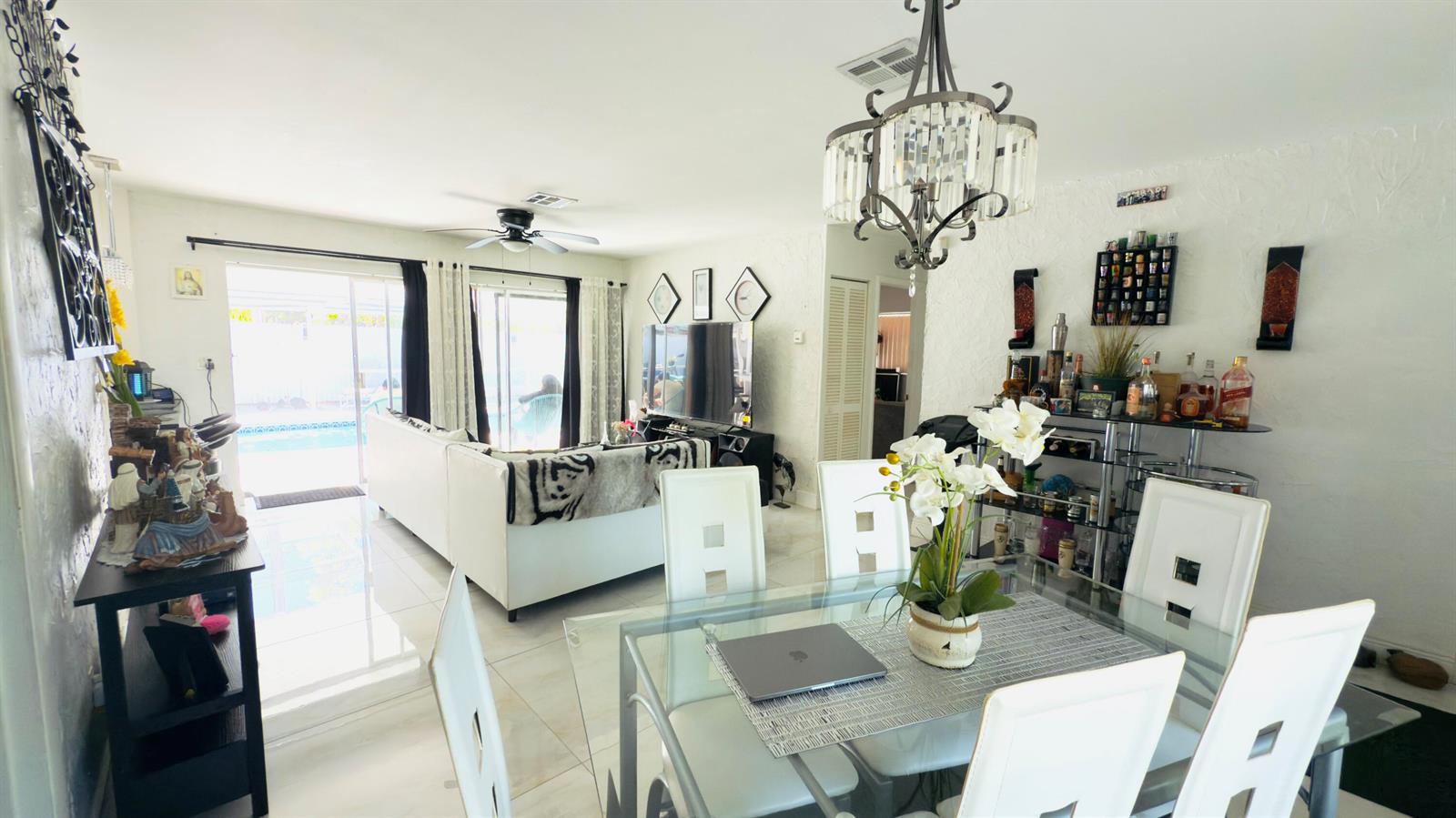 A bright, open-concept living and dining area features white tile floors and a glass table — 230 NE 25th Street, Pompano Beach FL 33064, POMPANO BEACH, FL