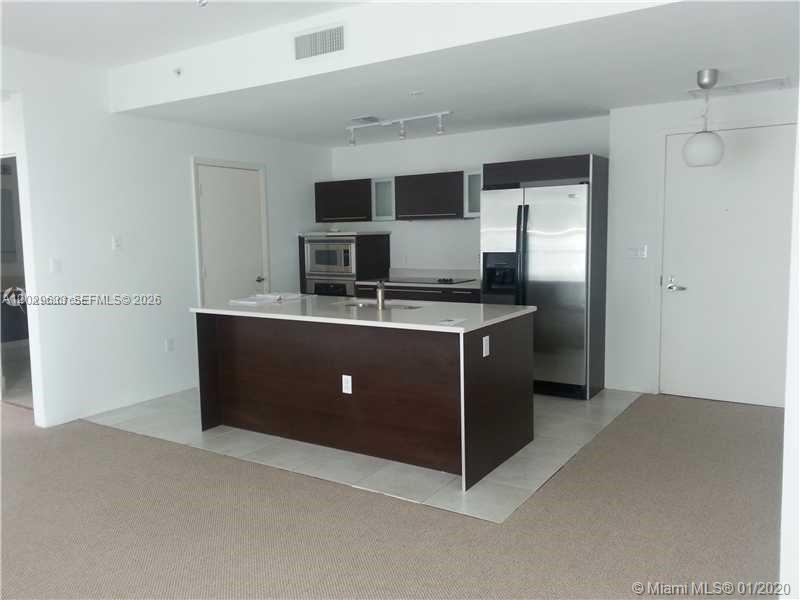 A kitchen features a dark wood island, stainless steel appliances, and dark upper cabinets — 1900 N Bayshore Dr # 3517, Miami FL 33132, MIAMI, FL
