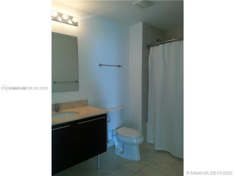 A bathroom features a dark wood vanity, a white toilet, and a shower with a curtain — 1900 N Bayshore Dr # 3517, Miami FL 33132, MIAMI, FL