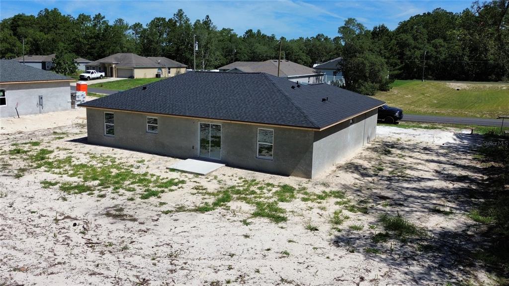 An aerial view of the rear exterior of a newly constructed house with gray stucco — 6164 SW 144TH LANE ROAD, OCALA, FL