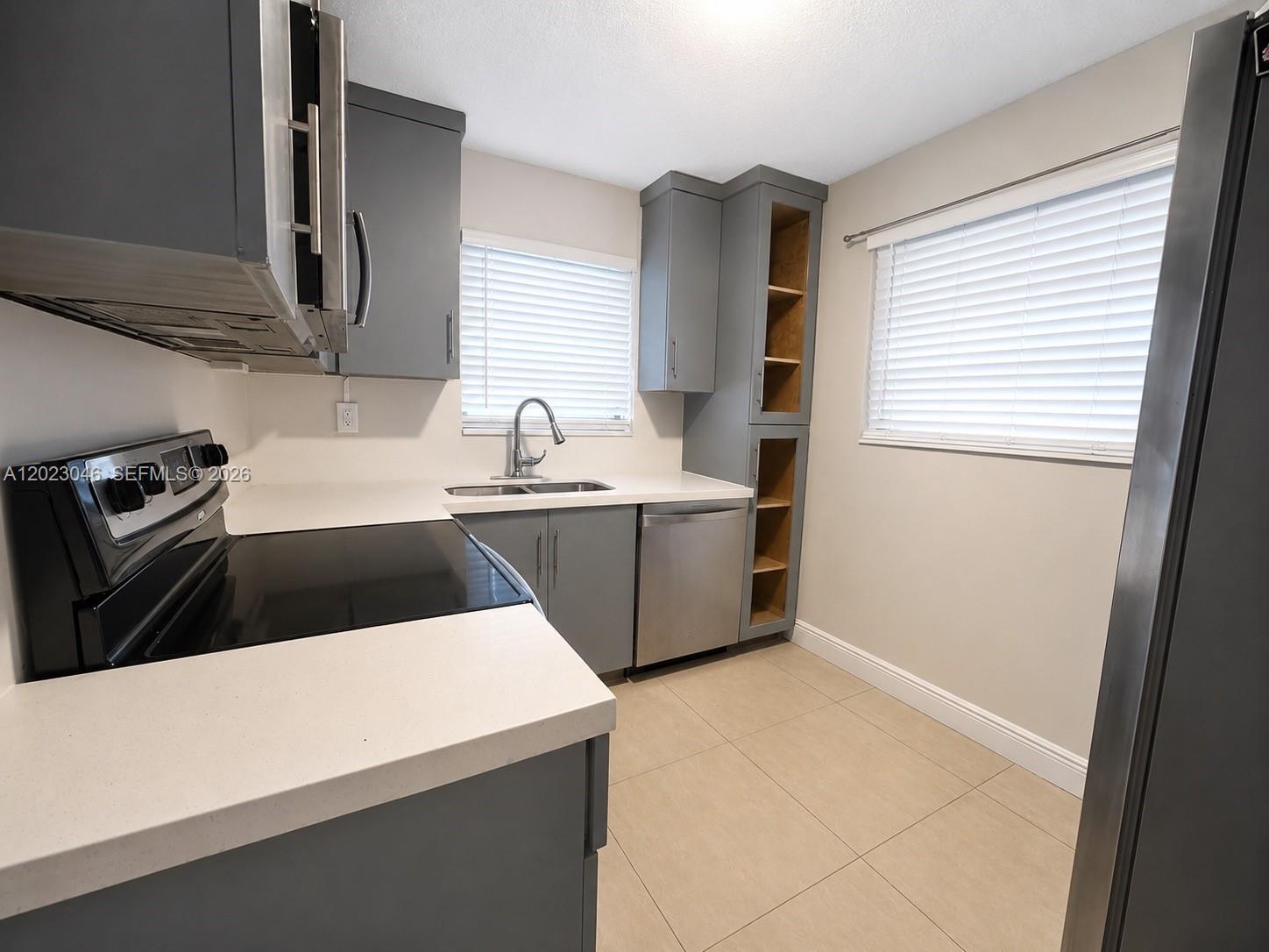 A kitchen features gray cabinets, stainless steel appliances, white countertops, and light tile flooring — 811 NW 6th Ave # 4, Pompano Beach FL 33060, POMPANO BEACH, FL