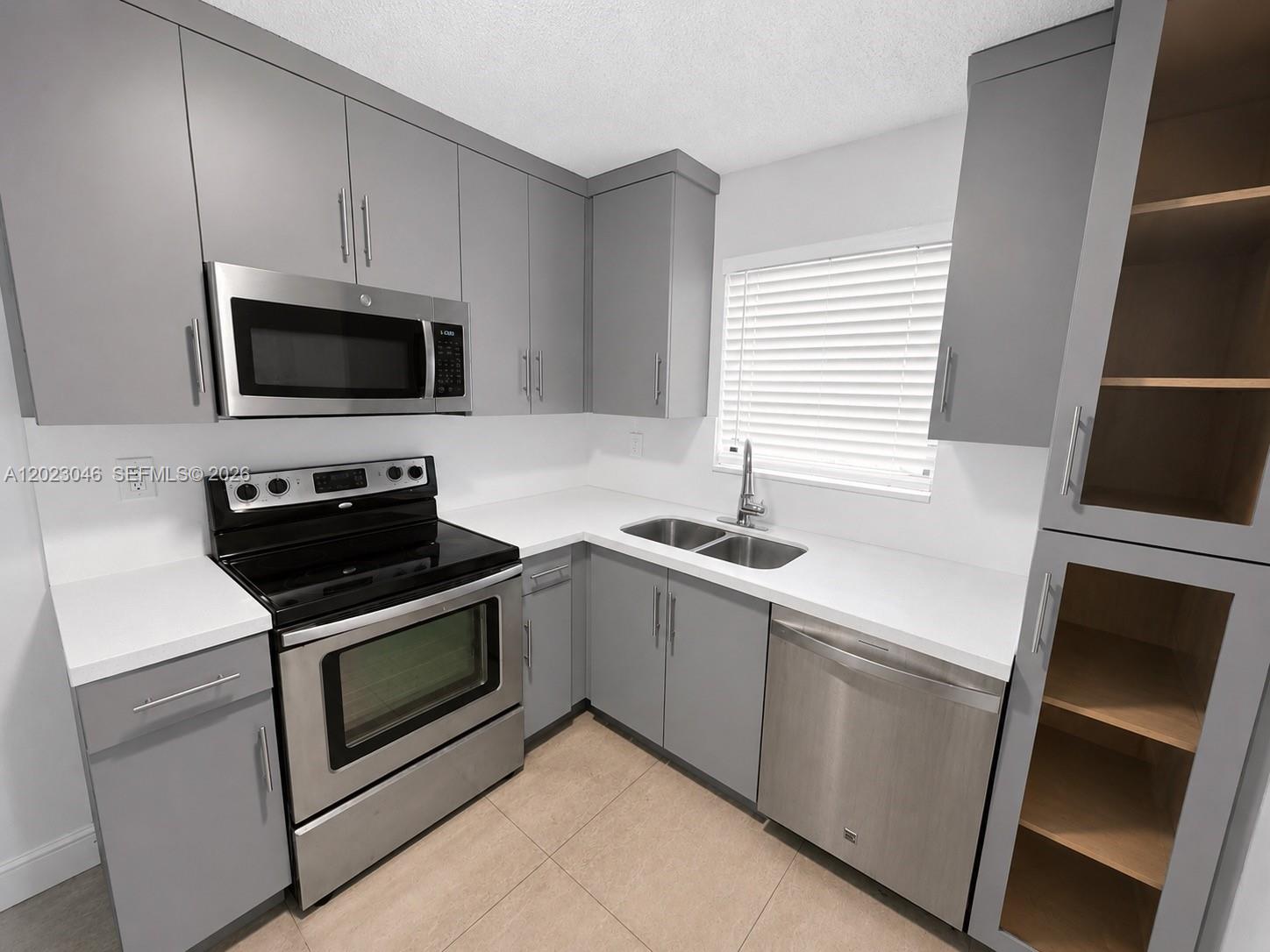A kitchen features gray cabinets, stainless steel appliances, white countertops, and light tile flooring — 811 NW 6th Ave # 4, Pompano Beach FL 33060, POMPANO BEACH, FL