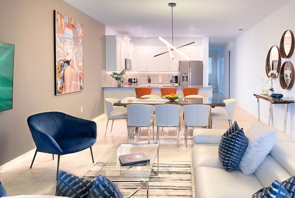 An open-concept living and dining area features a modern kitchen, glass table, and blue chair — 1139 DROP LANE UNIT 1139, DAVENPORT, FL