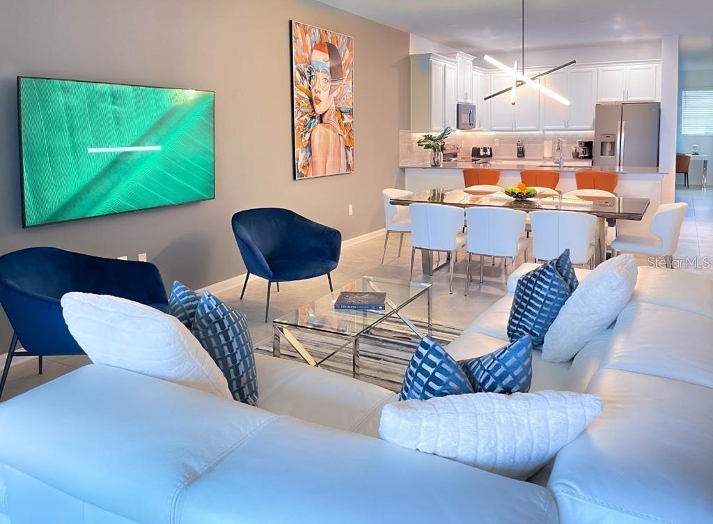 A living and dining area features a white sectional, blue chairs, and a modern kitchen — 1139 DROP LANE UNIT 1139, DAVENPORT, FL
